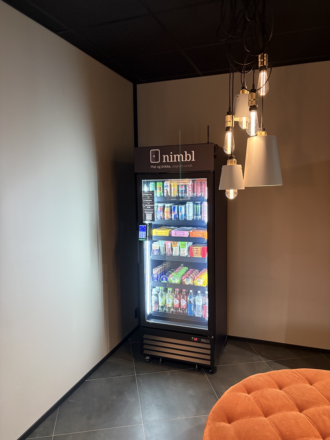Nimbl smart kjøleskap plassert i en lys lounge med møbler og hengelamper, hos en av våre lokasjoner